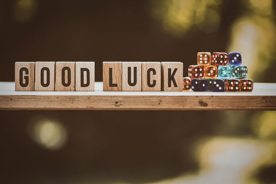 Wooden blocks spelling 'Good Luck' with colorful dice on a wooden surface.